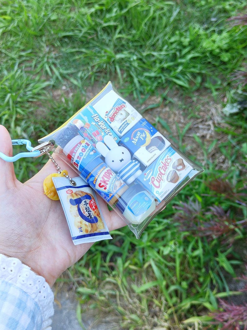 Pu&ograve; includere: Una bustina in plastica trasparente riempita con repliche in miniatura di cibo e snack, tra cui gomma Bazooka, burro di arachidi Skippy, Moon Pie, Hostess Donettes, CupCakes e una figura di Miffy. Un piccolo ciondolo a forma di snack &egrave; appeso.