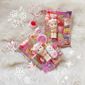 Pu&ograve; includere: Una tazza di ceramica bianca con manico nero e la scritta "But First, Coffee" in nero, in grassetto. La tazza &egrave; appoggiata su una superficie di legno.