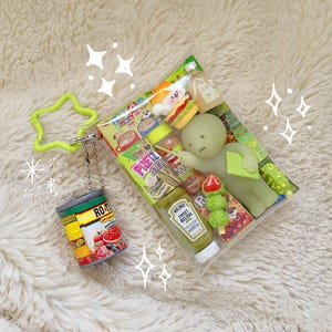 K&ouml;nnte beinhalten: Eine transparente Plastikt&uuml;te mit Miniatur-Lebensmitteln, darunter ein Hamburger, eine Flasche Heinz Sweet Relish und eine gr&uuml;ne Figur. Eine kleine Dose Ro-Tel-Tomaten h&auml;ngt an einem limettengr&uuml;nen sternf&ouml;rmigen Schl&uuml;sselanh&auml;nger.