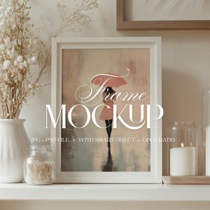 Könnte beinhalten: Ein weiß gerahmter Kunstdruck mit einer Frau mit Regenschirm im Regen. Die Worte "Frame Mockup" sind in eleganter Schrift dargestellt. Eine weiße Vase mit Trockenblumen, ein kleines Glas und Kerzen vervollständigen die Szene.