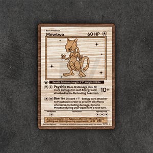 May include: Wooden plaque featuring a laser-etched image of a "Mewtwo" Pokémon trading card. The card design includes the Pokémon's name, HP, and attack details. The plaque is made of light-colored wood with a dark border.