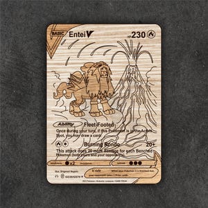 Puede incluir: Tarjeta de intercambio de Pokémon de madera con el personaje Entei V. La tarjeta tiene detalles grabados del personaje, un volcán y texto que describe las habilidades y el ataque del personaje. La tarjeta es rectangular con esquinas redondeadas.