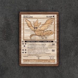 May include: Wooden Articuno Pokemon card. The card features a detailed laser-cut image of the Articuno character, with text including HP, attack descriptions, and the card's name. The card measures 5'7" in length and weighs 122 lbs.