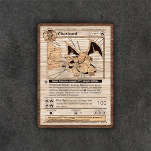 May include: Wooden Charizard Pokémon card. The card features a detailed engraving of Charizard, with text including "120 HP" and "Fire Spin." The card is made of wood and has a natural wood grain finish. The card measures 5'7" in length and weighs 200 lbs.