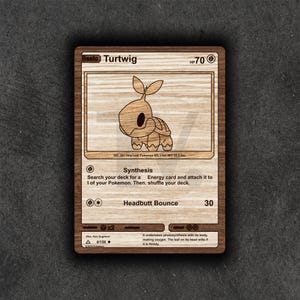 May include: Wooden Turtwig Pokemon card featuring a cartoon turtle illustration. The card includes the text "Turtwig", "HP 70", and "Headbutt Bounce 30". The card is made of wood and has a natural wood grain finish.
