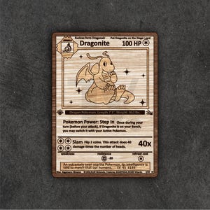 Może przedstawiać: Drewniana karta Dragonite Pokemon. Karta zawiera szczegółowy grawerunek postaci Dragonite, z tekstem, w tym "100 HP" i szczegółami ataku. Karta wykonana jest z jasnego drewna z ciemnobrązową obwódką.