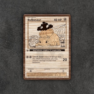 May include: Wooden Bulbasaur Pokémon card. The card features a detailed engraving of the Bulbasaur character, with text including "Bulbasaur", "40 HP", and "Leech Seed". The card is 2' 4" long and weighs 15 lbs.