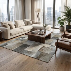 May include: A modern living room featuring a large beige sectional sofa, a dark wood coffee table, and two brown leather armchairs. A patterned rug in shades of gray and beige covers the floor. Tall windows offer a city view.