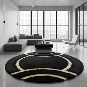 May include: A modern living room featuring a large, round black rug with a cream-colored geometric design. The rug sits on a concrete floor, with a gray sectional sofa, a black coffee table, and a white chair visible in the background.