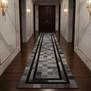 May include: A hallway runner rug with a geometric design. The rug has a patchwork pattern in shades of grey and black, with a black border. The hallway features marble walls, dark wood flooring, and wall-mounted lights.
