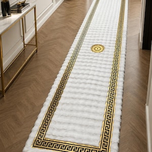 May include: A long, rectangular white runner rug featuring a plush, textured surface. The rug is bordered by a black and gold Greek key pattern and includes a circular gold medallion design centered in the middle of the runner's length.