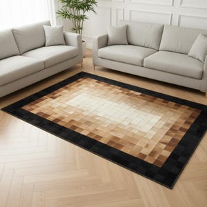 May include: A rectangular rug with a geometric pattern. The rug has a gradient design, shifting from a light beige centre to shades of brown and a black border. The rug is placed on a wooden floor.