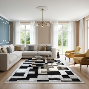 May include: A modern living room with a white sectional sofa, gold accent chairs, and a geometric black and white rug. A gold chandelier hangs above a marble coffee table. The room has large windows with white curtains.