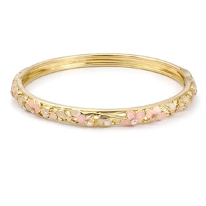 Op de afbeelding: Goudkleurige armband met een bloemenontwerp. De armband heeft roze en witte emaille bloemen en kleine, heldere kristallen. De bloemen zijn rond de omtrek van de armband gerangschikt.