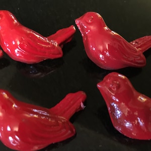 May include: Four red ceramic bird figurines. The birds are all facing the same direction and have a glossy finish.