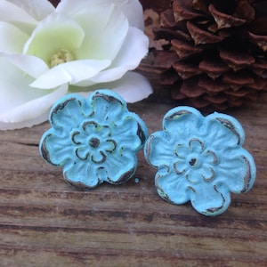 May include: Two turquoise blue metal flower-shaped drawer pulls with a distressed finish.