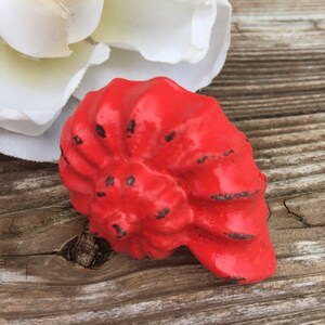 May include: A red seashell-shaped cabinet knob with a textured surface.