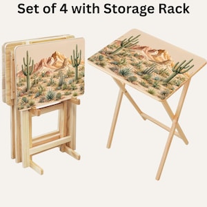 May include: A set of four light-colored wooden folding snack tables with a storage rack. The rectangular tabletops feature a printed desert landscape illustration with cacti and mountains. The text "Set of 4 with Storage Rack" is visible.