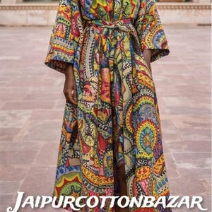 May include: A long, colorful kimono-style robe with a vibrant, intricate pattern. The robe features a tie belt and wide sleeves. The text "JAIPURCOTTONBAZAR" is displayed at the bottom. The robe is made of a lightweight fabric.