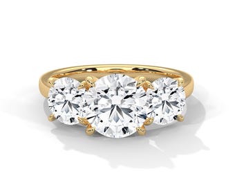 May include: A gold engagement ring featuring three clear, round-cut gemstones. The ring has a classic design with a smooth, polished gold band. The gemstones are held in place by prongs, creating a timeless look.
