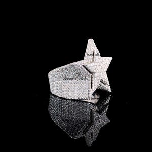 May include: A silver-toned star-shaped ring, encrusted with numerous small, sparkling stones. The ring's design features a prominent star shape, with the band and star covered in the stones. The ring is displayed on a reflective black surface.