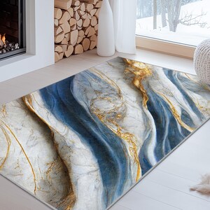 Può includere: Un tappeto rettangolare con un design marmorizzato. Il tappeto presenta un motivo fluido di bianco, blu e oro. È posizionato su un pavimento in legno chiaro davanti a un camino.