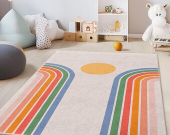 May include: A rectangular rug with a cream background features a large yellow circle and two sets of rainbow arches in shades of red, orange, green, and blue. The rug is placed on a light wood floor in a child's room.