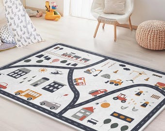May include: A rectangular children's play rug with a road map design. The rug features roads, buildings, vehicles, and other illustrations in various colors. The rug is bordered with a dark blue trim and is placed on a light-colored wooden floor.