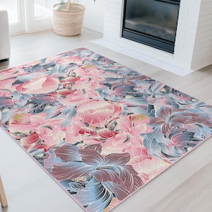May include: A large area rug with a floral pattern in shades of pink, blue, and purple. The rug features a detailed design of large flowers and leaves, creating a vibrant and artistic look. The rug is placed in a living room setting.