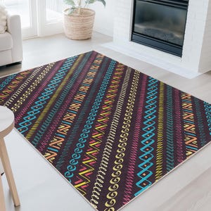 Peut inclure: Un tapis rectangulaire avec un fond marron foncé et des rayures diagonales colorées. Les rayures présentent divers motifs dans des tons de bleu, jaune, rose et orange. Le tapis est posé sur un sol clair dans un salon.