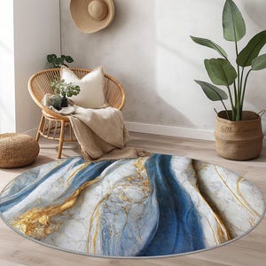 May include: A round area rug with a marble design. The rug features a white background with blue and gold veining. The rug is on a wooden floor in a room with a wicker chair and a potted plant.