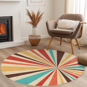 May include: A round area rug with a retro sunburst design. The rug features a pattern of radiating stripes in shades of red, orange, yellow, brown, and teal. The rug is placed on a wooden floor in a living room setting.