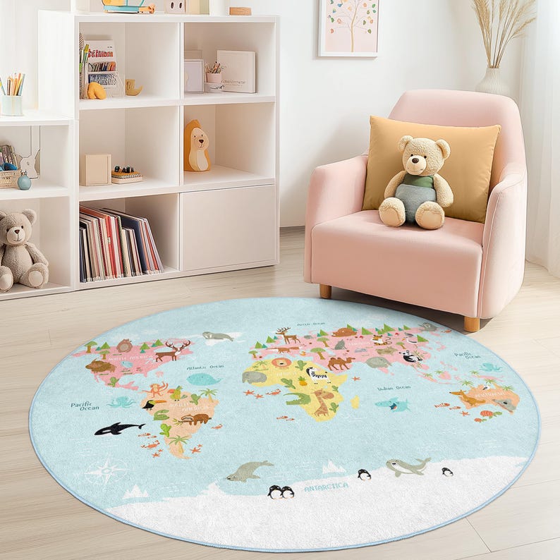 May include: A round, light blue rug featuring a world map design with continents in various colors and illustrations of animals and landmarks. The rug is placed on a light-colored floor, with a pink armchair and a white bookshelf in the background.