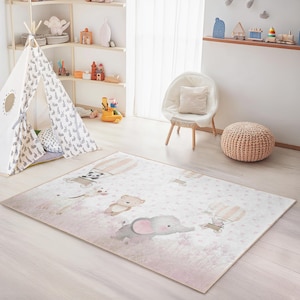 Pode incluir: Um tapete retangular com um padrão rosa e branco com animais de desenho animado e balões de ar quente. O tapete está no quarto de uma criança, com um tipi, uma cadeira e prateleiras no fundo.