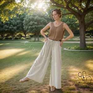 Può includere: Una persona indossa una canotta marrone abbottonata e pantaloni color crema a gamba larga in un parco. I pantaloni hanno una vita con coulisse. Lo sfondo presenta erba verde, alberi e luce solare. Il logo "Linnoras" è nell'angolo in basso a destra.