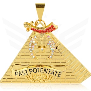 以下が含まれることがあります： 「PAST POTENTATE」の文字が入ったバナーが付いた、ピラミッドデザインのゴールドカラーのペンダント。ペンダントには、ピラミッドの上に赤と虹色の宝石がちりばめられたアクセントがあります。ピラミッドはレンガのような模様で詳細に描かれています。