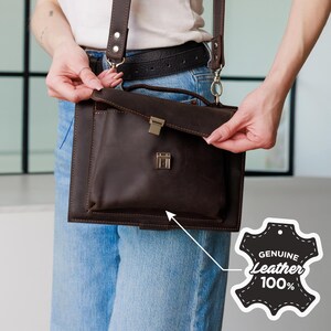 May include: A dark brown leather crossbody bag with a rectangular shape and a flap closure. The bag has a front pocket and a shoulder strap. The image includes a tag that says "GENUINE Leather 100%"