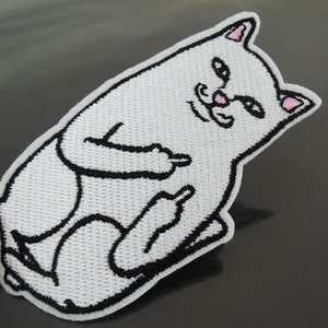 May include: White embroidered iron-on patch of a cat giving the middle finger. The cat has pink ears and a black mustache.