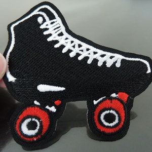 May include: Black and white embroidered roller skate patch with red wheels. The patch is made of fabric and has a stitched edge.