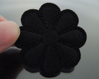May include: Black felt flower applique with a scalloped edge. The flower has a simple design with five petals.