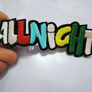 Könnte beinhalten: Ein bunter gestickter Aufnäher mit dem Wort "ALLNIGHT" in verschiedenen Farben, darunter Weiß, Rot, Blau, Gelb und Grün.