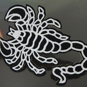 May include: White embroidered scorpion patch on a black background. The scorpion is outlined in white and has a detailed design.