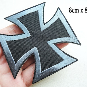 Puede incluir: Parche de cruz de hierro negro con borde bordado plateado. El parche mide 8 cm por 8 cm.