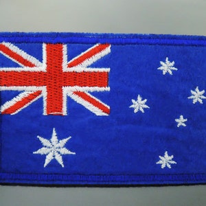 May include: A blue embroidered patch featuring the Australian flag. The flag displays a Union Jack in the top left corner and a constellation of five white stars on a blue background.