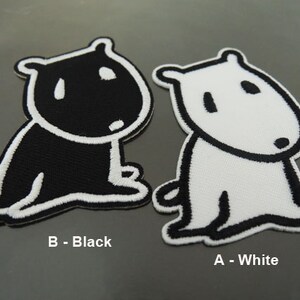 Könnte beinhalten: Zwei Bügelbilder mit einem Cartoon-Hund, eines schwarz und eines weiß. Der Hund sitzt mit gekreuzten Beinen und hat ein einfaches Design. Die Patches sind mit "A - Weiß" und "B - Schwarz" beschriftet.