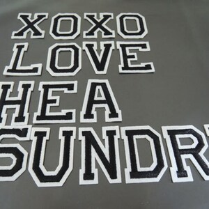 Könnte beinhalten: Schwarze Filzbuchstaben mit weißen Umrandungen, die "XOXO LOVE HEA SUNDRI" buchstabieren.