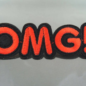 May include: Red embroidered letters spelling "OMG!" on a black felt background.