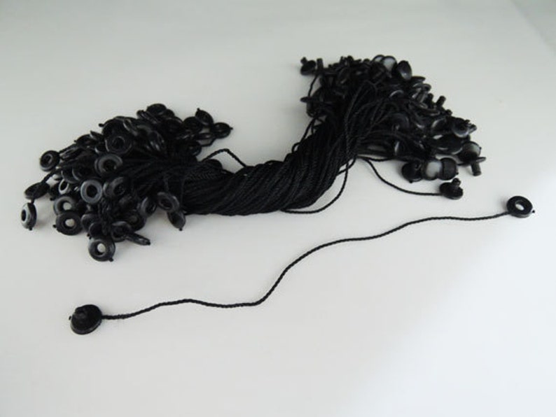 May include: A bulk pack of black string with black plastic loops at the end. The string is bundled together and some of the loops are loose.