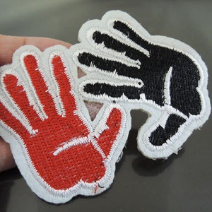 May include: Two embroidered iron-on patches, one red and one black, each depicting a hand with five fingers. The patches are on a white background.