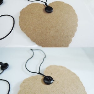 May include: Two brown heart-shaped paper tags with black string and black plastic fasteners. The tags are blank and ready for writing.